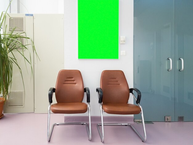 Sala de espera en el hall del hospital con un tablero de pantalla verde. Maqueta lista