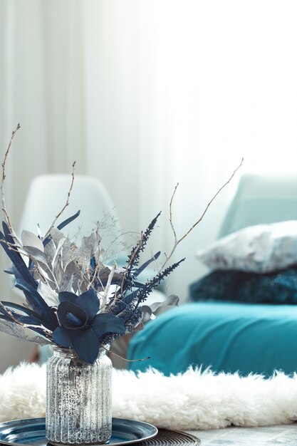 Sala de estar moderna, con flores artificiales en un jarrón y artículos de decoración del hogar en una mesa de luz de madera.