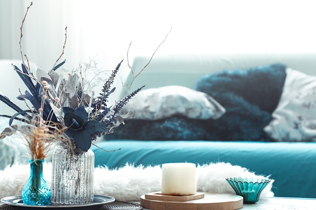 Sala de estar moderna, con flores artificiales en un jarrón y artículos de decoración del hogar en una mesa de luz de madera.