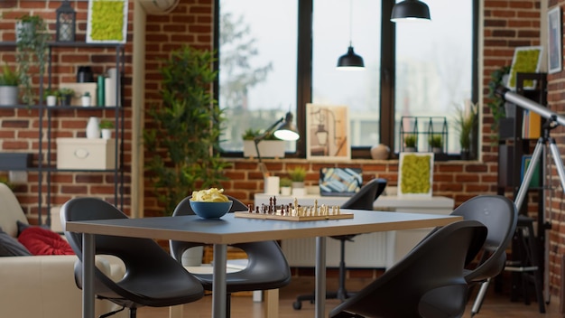 Sala de estar vacía decorada para divertirse reuniéndose con amigos, tomando bebidas alcohólicas y bocadillos. Nadie en apartamento con modernos juegos de mesa y ajedrez para disfrutar de reuniones en casa para el entretenimiento.