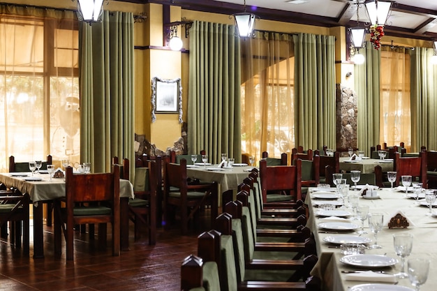 Sala de restaurante de estilo clásico con sillas y cortinas de madera verde.