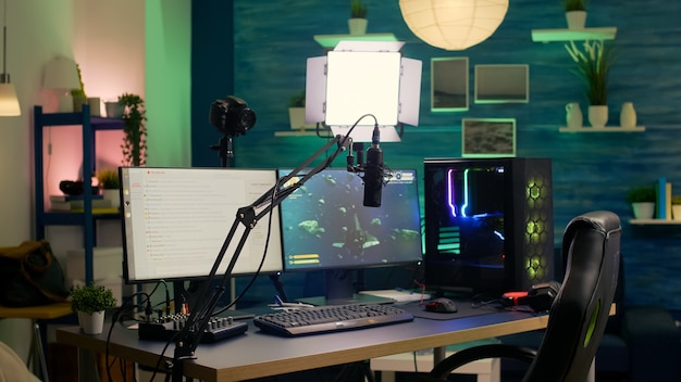 Sala de transmisión vacía con una potente computadora profesional, teclado y mouse RGB, auriculares y micrófono