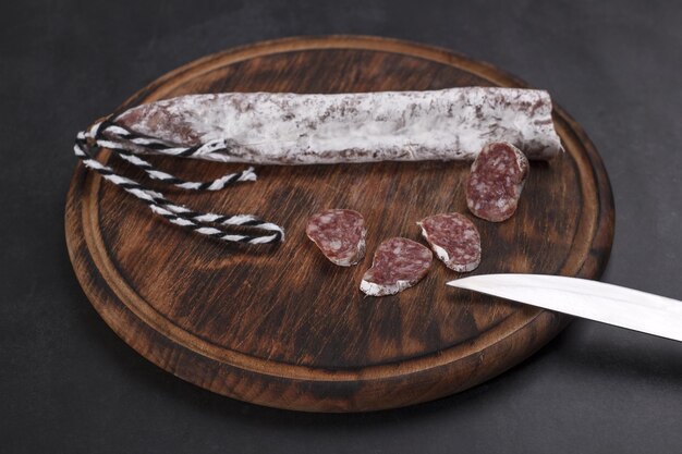 Salchicha de cerdo fuet tradicional catalana finamente curada con trozos en rodajas sobre una tabla de madera
