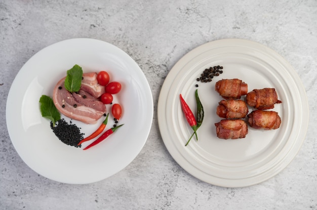 Foto gratuita la salchicha envolvió el vientre de cerdo pegado en un plato en un plato y el vientre de cerdo en un plato blanco.