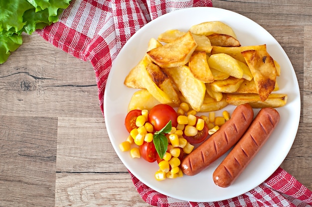 Salchicha con papas fritas y verduras en un plato