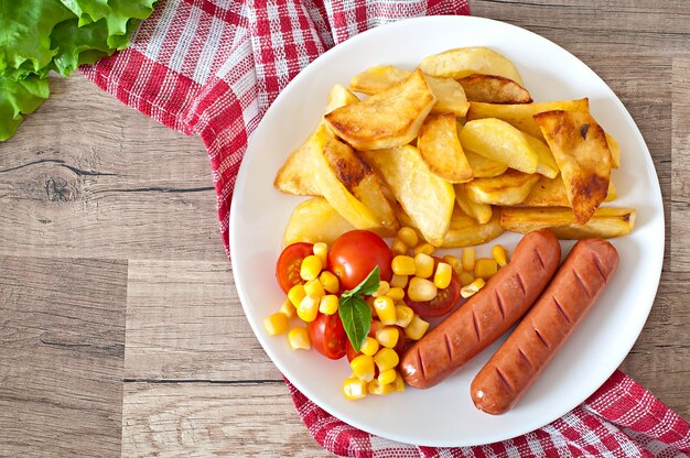 Salchicha con papas fritas y verduras en un plato