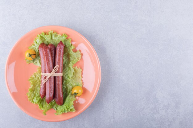 Salchichas ahumadas atadas con cuerda en plato naranja.