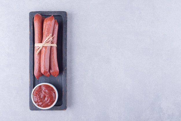 Foto gratuita salchichas ahumadas y salsa de tomate en un plato oscuro.