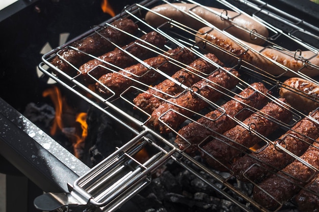 Salchichas chisporroteantes asadas oscuras en la barbacoa