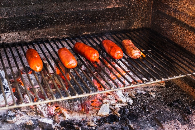 Salchichas a la parrilla sobre carbón quemado en una barbacoa portátil