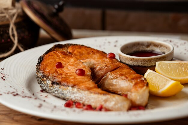 Salmón frito con semillas de granada y rodajas de limón.