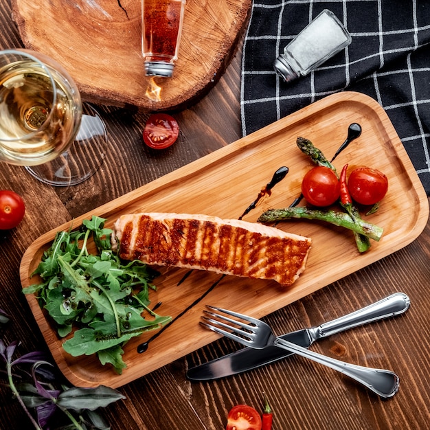 Salmón frito con verduras en la vista superior del tablero de madera