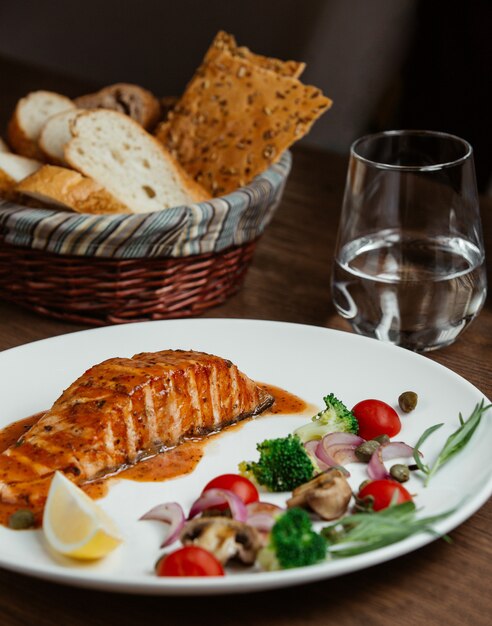 salmón a la parrilla en salsa con limón, brócoli, tomate, cebolla y estragón