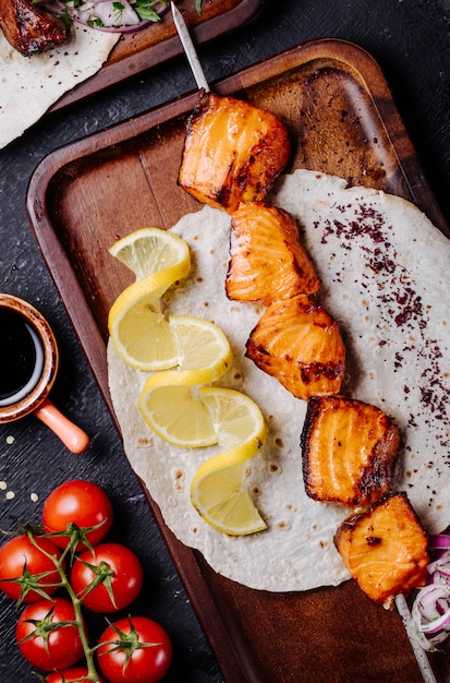 Salmón a la parrilla servido en pan lavash con rodajas de limón.