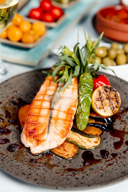 Salmón a la parrilla servido con vegetales a la parrilla y limón