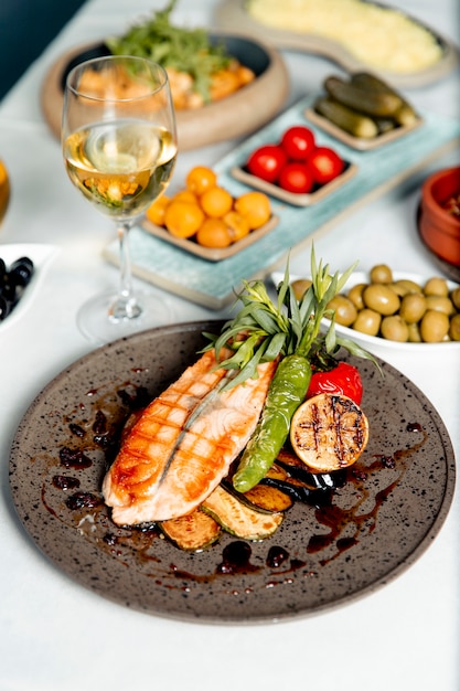 Salmón a la plancha con verduras y limón servido con copa de vino.