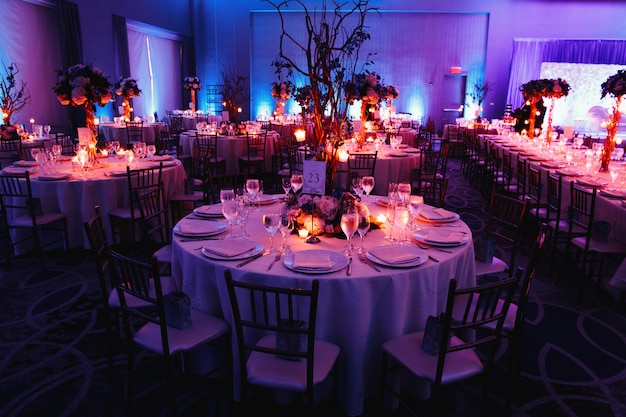 Salón de bodas decorado con velas, mesas redondas y centros de mesa
