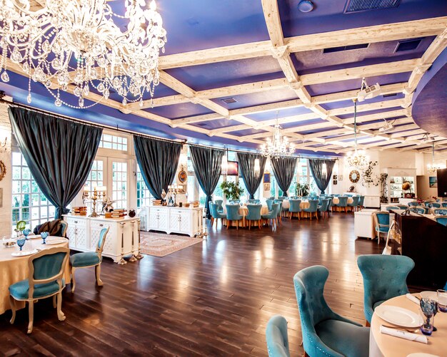 Salón del restaurante con sillas turquesas, ventanas francesas, techo de color azul marino