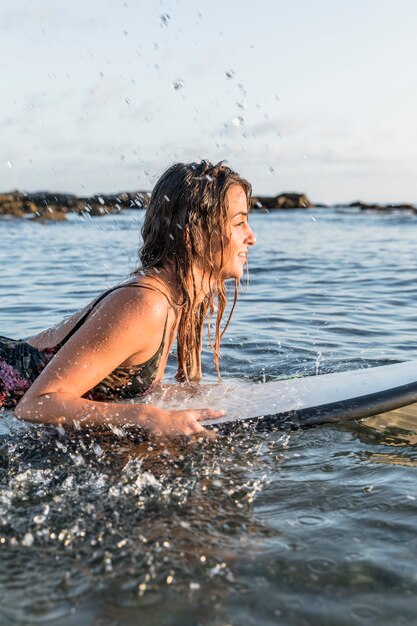 Salpicaduras de agua cerca de la mujer en la tabla de surf