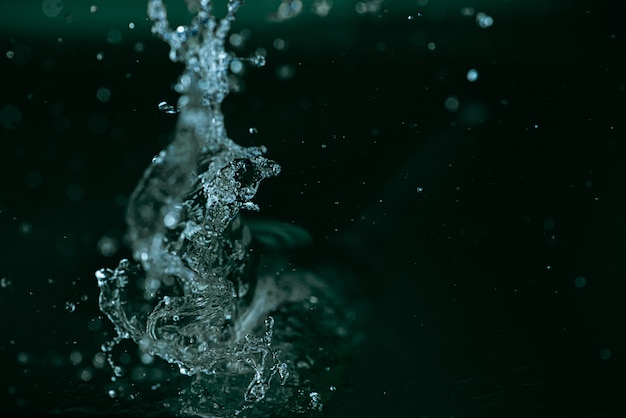 salpicaduras de agua en movimiento sobre un fondo verde oscuro