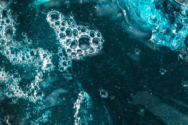Salpicaduras y espuma delgada en agua azul