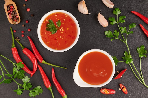 Foto gratuita salsa de chile rojo picante. ketchup de tomate, salsa de chile, puré con ají, verduras, tomates y ajo. en la superficie de piedra negra. vista superior