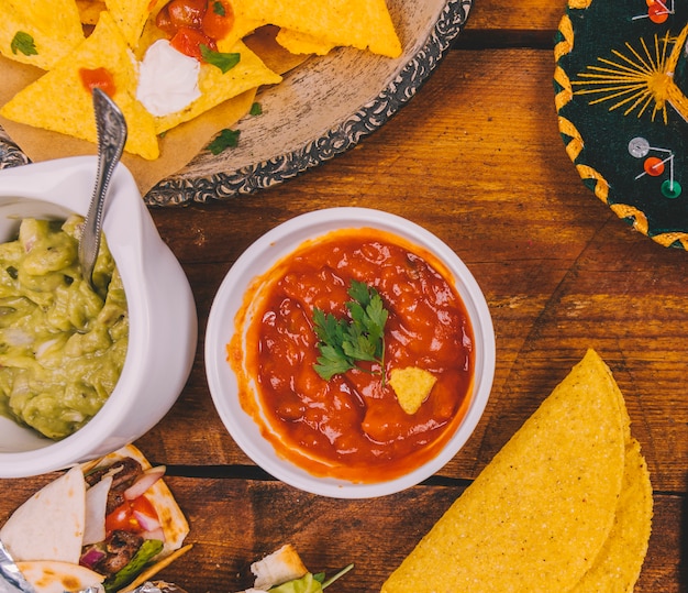 Salsa de salsa guacamole; sabrosos nachos mexicanos; Tortilla y envolver los tacos mexicanos en mesa de madera.