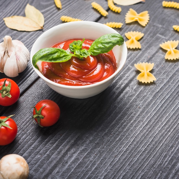 Salsa de tomate fresca preparada con hojas de albahaca sobre mesa