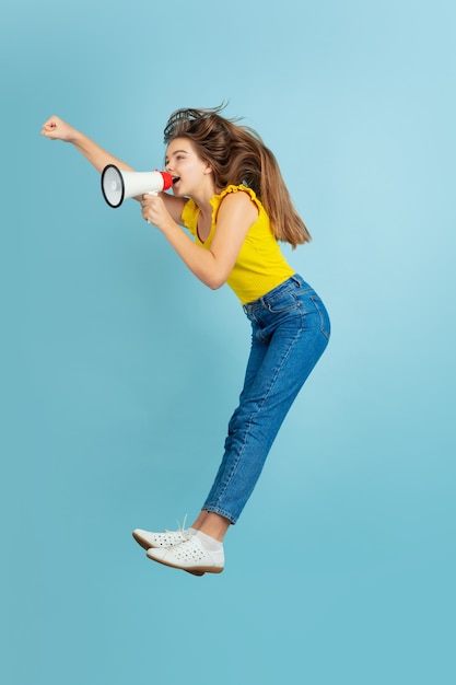 Foto gratuita saltando alto, pidiendo ventas. retrato de muchacha adolescente caucásica en azul