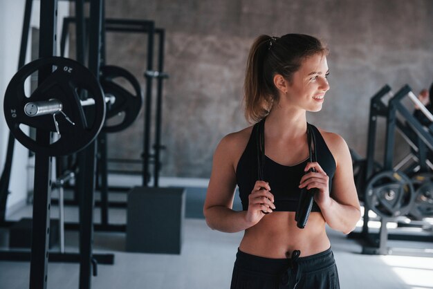 Saltar la cuerda en el cuello. Hermosa mujer rubia en el gimnasio en su fin de semana