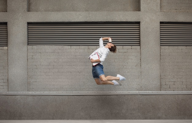 Saltar joven buinessman delante de edificios, en la carrera en salto alto