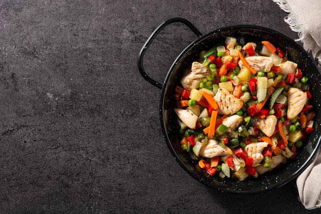 Salteado de pollo y verduras sobre fondo de piedra negra