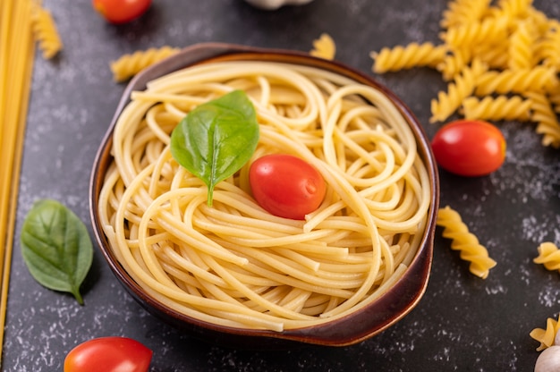 Saltear los espaguetis en un plato gris con tomates y albahaca