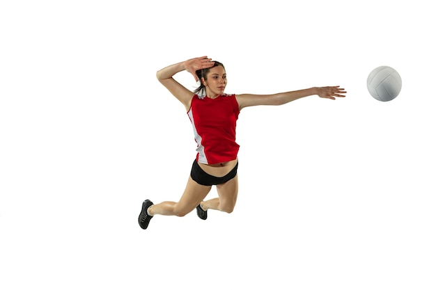 En salto y vuelo. Jugador de voleibol femenino joven aislado sobre fondo blanco de estudio. Mujer en ropa deportiva y zapatillas de deporte, jugando. Concepto de deporte, estilo de vida saludable, movimiento y movimiento.