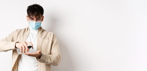 Foto gratuita salud covid y concepto de cuarentena joven hispano con gafas y mascarilla usando desinfectante para manos