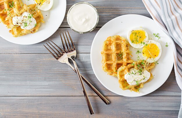 Saludable desayuno o merienda. Gofres de patata y huevo cocido en mesa de madera gris. Vista superior. Lay Flat