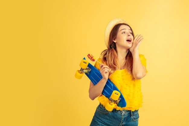 Saludar, llamar. Retrato de mujer caucásica sobre fondo amarillo de estudio.