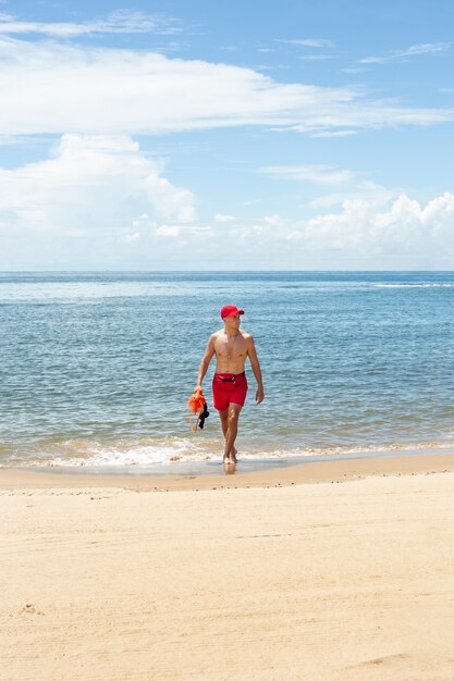 Salvavidas caminando en la playa tiro completo