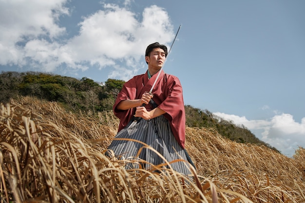 Foto gratuita samurai con espada en un campo