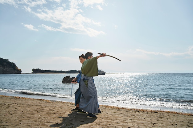 Foto gratuita samurai luchando con espadas en la playa