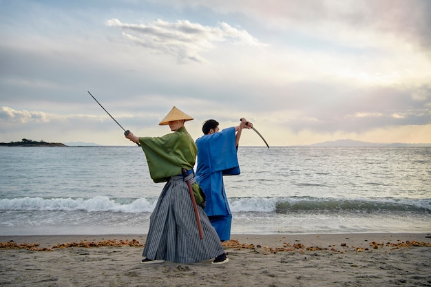 Foto gratuita samurais peleando con espadas en la playa