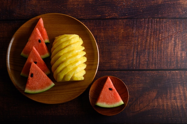 Foto gratuita sandía y piña cortada en trozos en un plato de madera