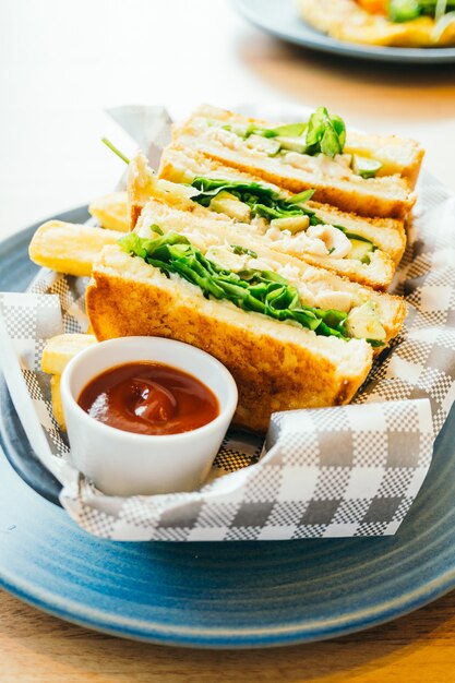 Sándwich con aguacate y carne de pollo con papas fritas.