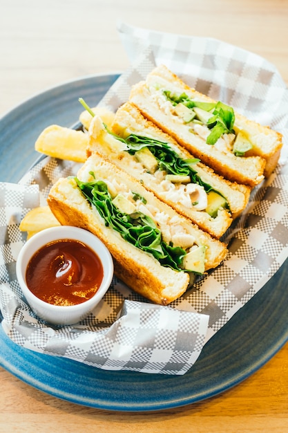 Sándwich con aguacate y carne de pollo con papas fritas.