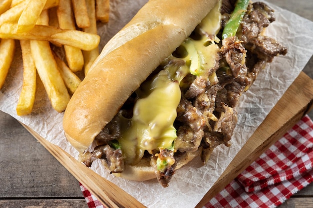 Sándwich de bistec con queso de Filadelfia en mesa de madera Sándwich tradicional de Filadelfia