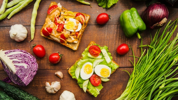 Foto gratuita sándwich de carne deliciosa con diferentes verduras saludables en mesa de madera