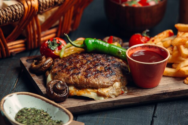 Sándwich de carne a la parrilla con queso y verduras junto con papas fritas