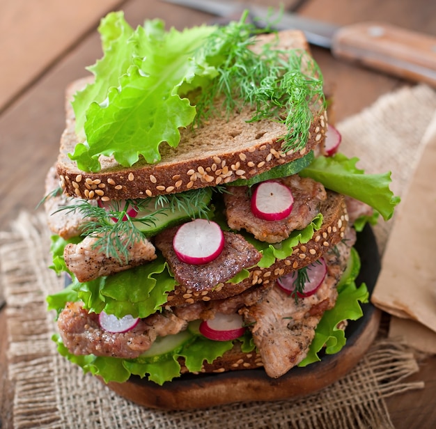 Sandwich con carne, verduras y rebanadas de pan de centeno.