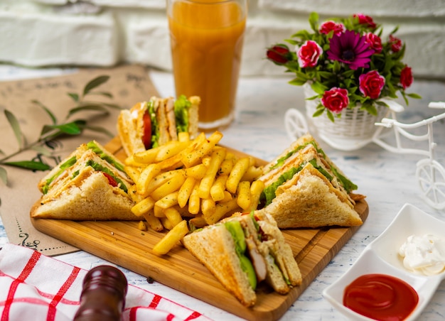 Sándwich Club servido con papas fritas y refrescos, mayonesa, salsa de tomate