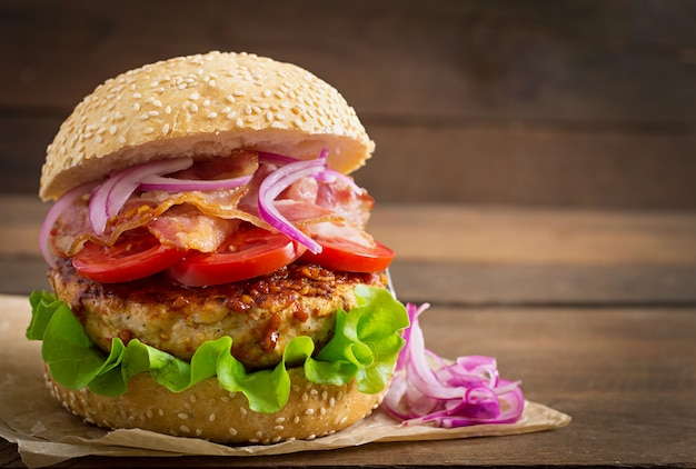 Sándwich grande - hamburguesa con carne de res, cebolla roja, tomate y tocino frito.